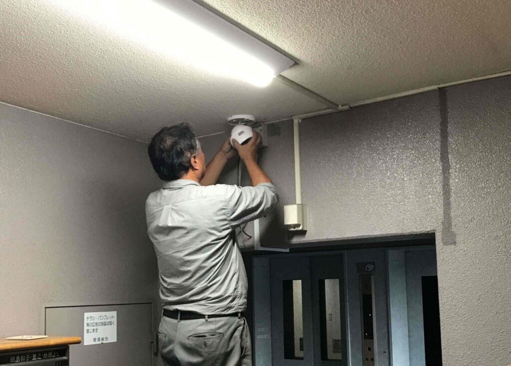 室内で脚立に乗って防犯カメラを取り付ける作業員