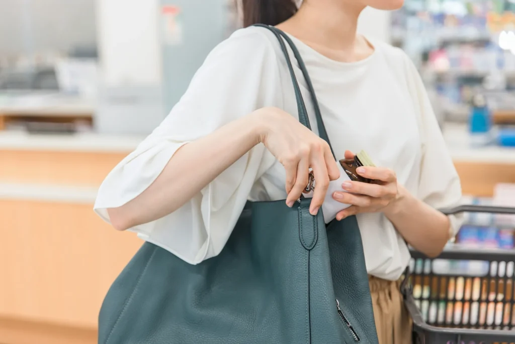 店舗内で商品をバッグに入れようとする人物のイメージ